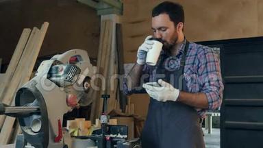 木匠在电锯附近的车间里喝咖啡，在智能手机上做些什么。